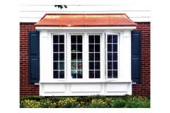 Outside View Of A Bow Window Creating Charm And Character For A Home With Blue Shutters On Both Sides And An Awning Above It