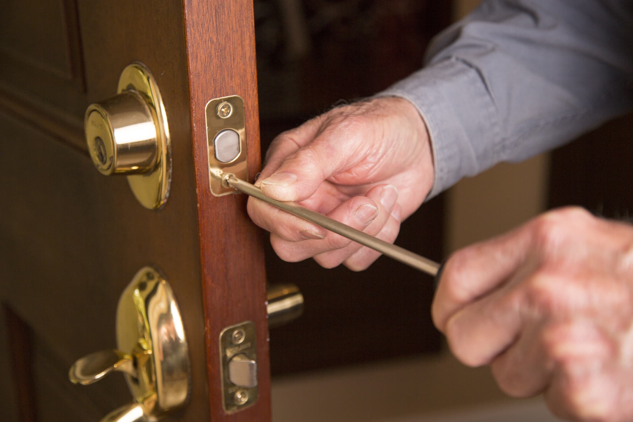 Replacement door specialist screwing hardware onto new front entryway door