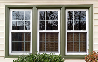 Array of three residential double-hung windows trimmed in green