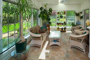 Plants in a white sunroom with white wicker furniture