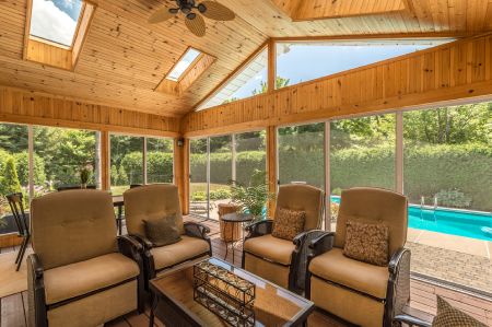 Wooden patio screened in poolside with beautiful tan and brown furniture