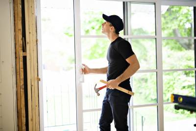 Worker holding hammer inspecting door installation