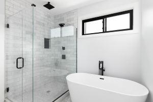 Large tiled shower with glass door next to bathtub in bathroom 